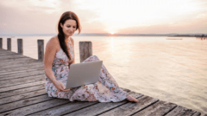 Angelika mit Laptop auf einem Steg am See