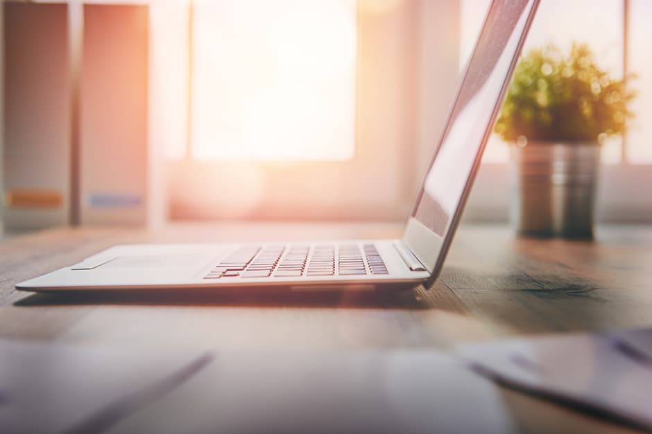Laptop auf einem Schreibtisch im warmen Sonnenlicht